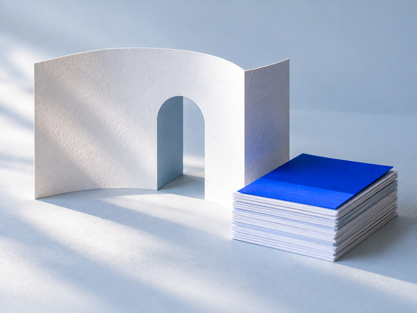 A white card model of an open doorway beside a stack of paper pages.