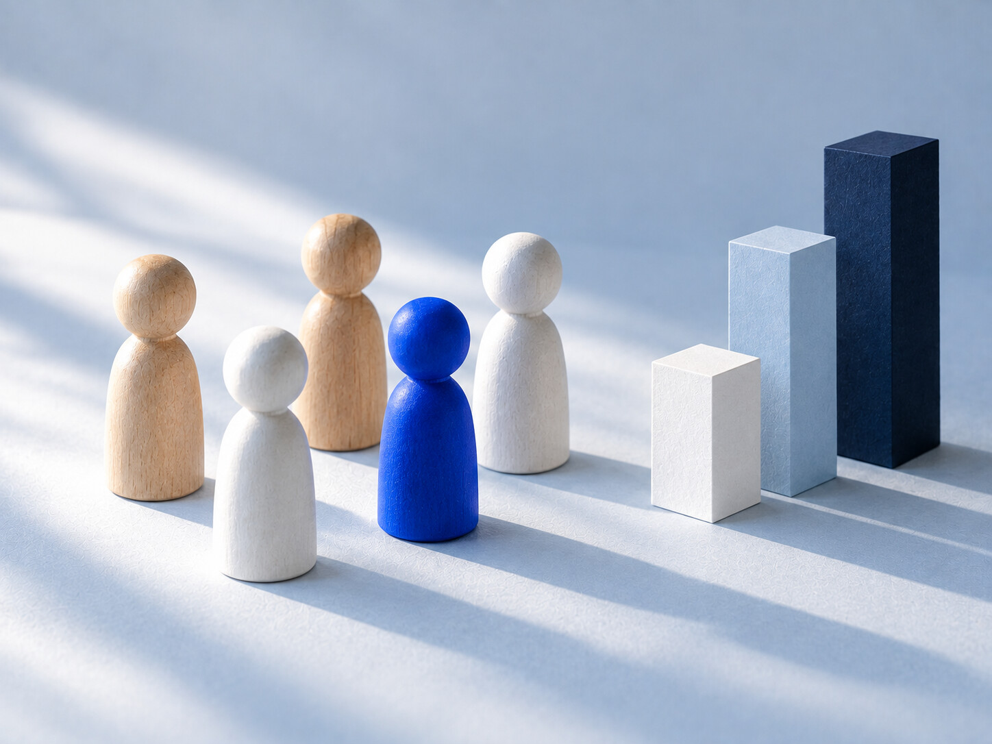 Wooden peg figures stand beside a small paper bar chart.