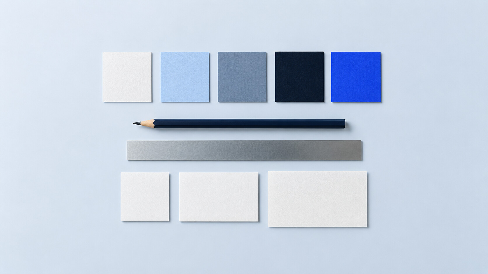 A small, neatly aligned set of colour swatches, paper tiles, a pencil and a ruler.
