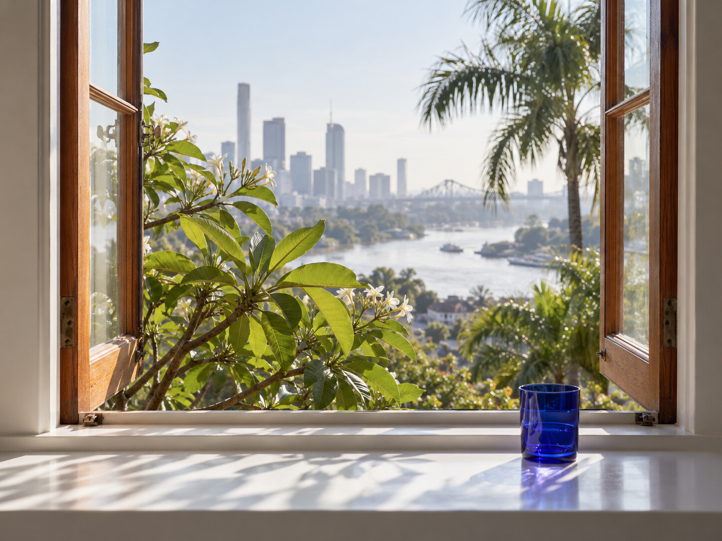 Morning light through the studio window, with greenery and the Brisbane skyline beyond.